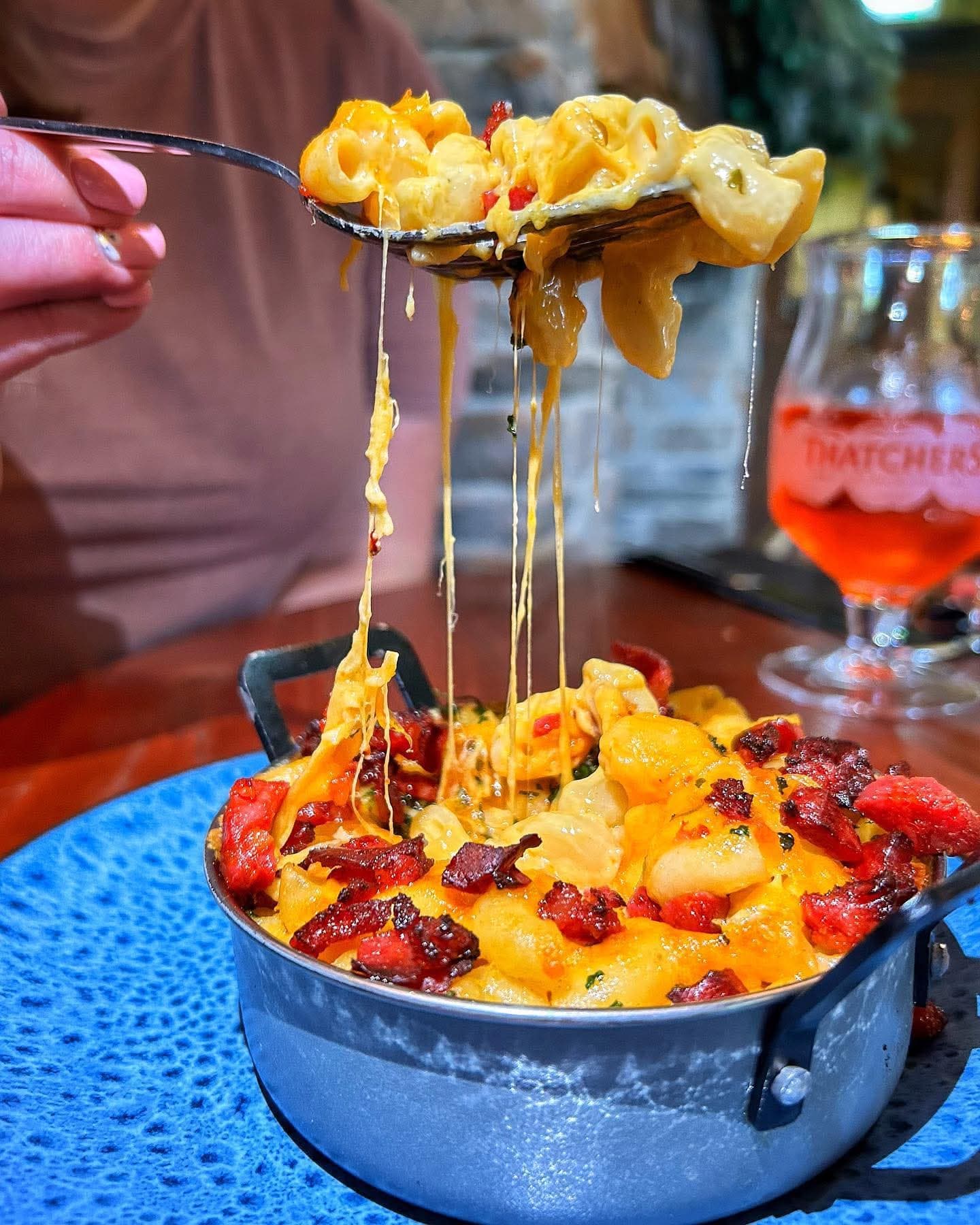 A loaded mac and cheese topped with crispy chorizo and bacon, served in a pan with a cheese pull at The Lakeside Inn