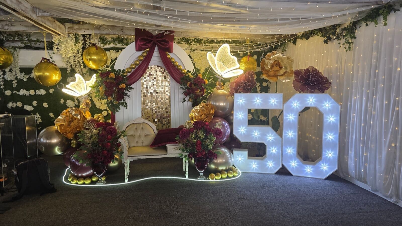 A milestone birthday styled in a function room at The Lakeside Inn, with a balloon arch, light up numbers and floral backdrop