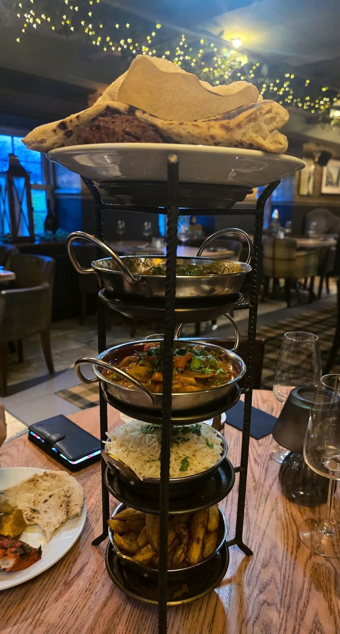 A towering curry stand with curry, rice, chips, poppadoms and naan at The Lakeside Inn