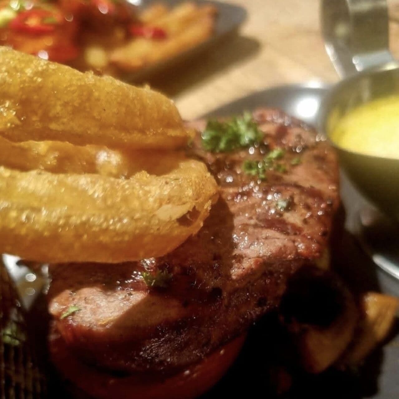 A grilled steak topped with crispy onion rings and peppercorn sauce at The Lakeside Inn