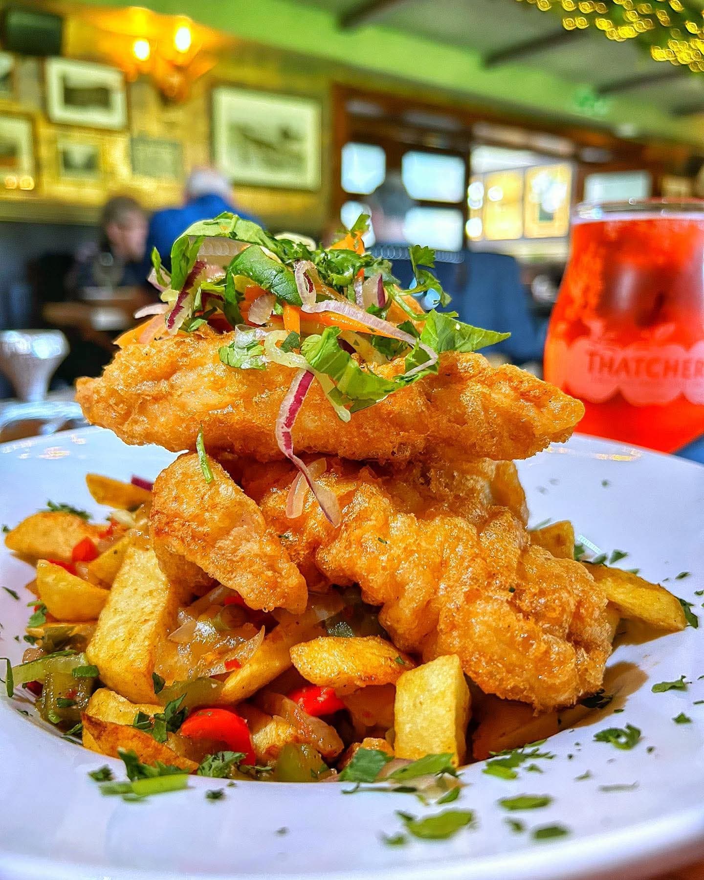 A towering stack of crispy battered strips piled high over seasoned chips and peppers at The Lakeside Inn