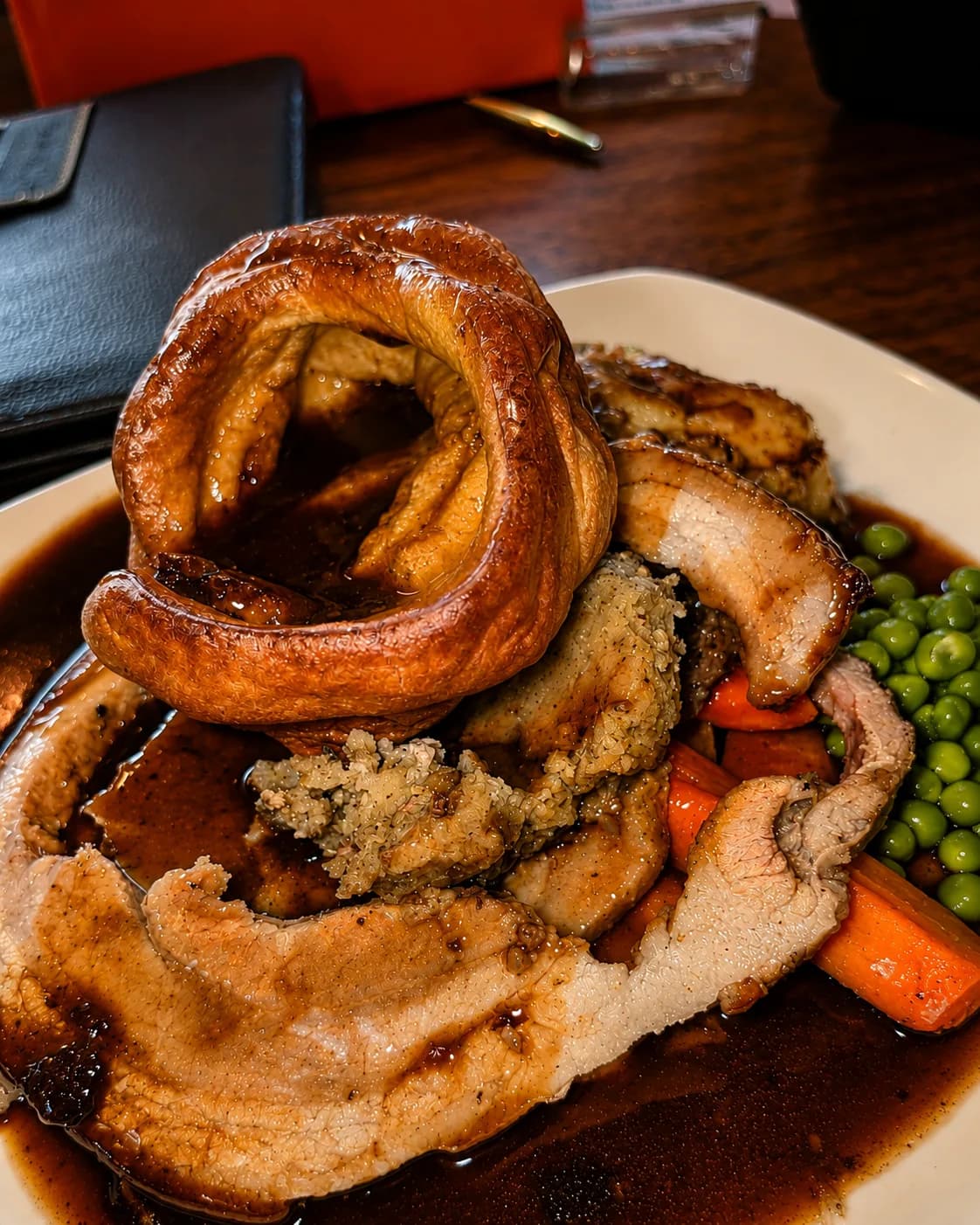 A Sunday roast at The Lakeside Inn with sliced roast meats, a giant Yorkshire pudding, stuffing, carrots, peas and rich gravy